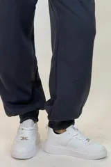 Pantalon deportivo tipo babucha de color beige, con cintura elástica ajustable mediante cordón y puños elásticos en los tobillos.