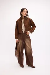 Pantalón de jean estilo baggy, de corte amplio y tiro medio, confeccionado en denim negro con textura de pana fina. Presenta diseño de cinco bolsillos, cierre frontal con botón metálico y cremallera, y perneras holgadas.