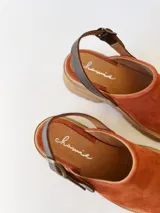 Zueco de cuero color ladrillo con correa trasera ajustable color marrón oscuro y suela track color marrón claro.