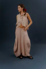 Pollera larga de lino color gris topo, de diseño amplio con volumen, movimiento y bolsillos delanteros. Cuenta con elástico en la cintura y detalles de pinzas y sobretelas en los laterales.