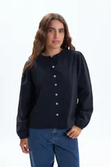 Remera de manga larga color negro, con cuello redondo y cierre frontal de botones. Presenta mangas abullonadas con puños elásticos.
