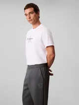 Pantalón de tejido grueso de punto liso con cintura elástica, corte ceñido y largo al tobillo. Presenta un diseño minimalista con logo de la marca bordado en el muslo.