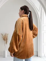 Campera de terciopelo color camel, con cierre frontal, cuello alto y bolsillos laterales con ribete de cuero sintético.