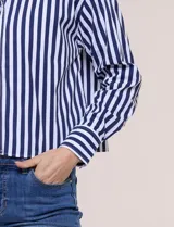 Camisa crop de manga larga con diseño de rayas verticales verdes y blancas, cuello camisero clásico y cierre frontal de botones.