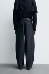Pantalón de corte balloon fit, color negro, con bolsillos laterales de vivo y bolsillos traseros con solapa. Presenta cierre frontal con cremallera y botón.