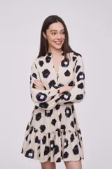 Vestido corto con estampado animal print en tonos beige, negro y azul. Tiene cuello mao, mangas largas con puños elásticos, cintura elastizada y falda con volantes.