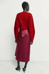 Falda midi de tiro medio confeccionada en tejido satinado con estampado de lunares. Presenta un diseño envolvente con detalle de volante lateral y cierre posterior con cremallera oculta.