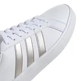 Championes urbanos Adidas modelo Grand Court Base 2.0, color blanco con las icónicas tres franjas laterales en tono gris metalizado. Presentan un diseño inspirado en los años 70 con suela tipo cupsole de caucho y cierre mediante cordones.