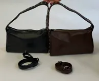 Cartera tipo morral de cuero sintético con cierre superior, asa de hombro con tachas metálicas y correa larga regulable desmontable.