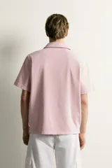 Polo de corte regular fit en color rosado con efecto lavado. Presenta cuello solapa, cierre frontal de botones y mangas cortas con acabados en rib.