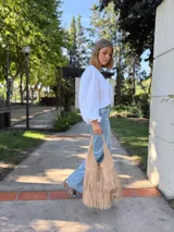 Cartera tipo hobo de cuero color beige con flecos en dos niveles.