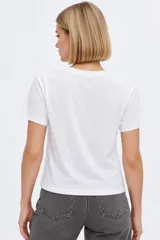 Remera de manga corta de algodón, color blanco, con cuello redondo y estampado frontal estilo collage con gráficos y texto en tono bordó.