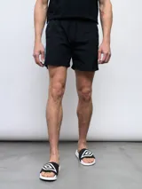 Short de baño negro con una banda vertical blanca en el lateral con el logo de Umbro en color rosa.