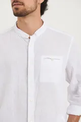 Camisa de cuello mao y manga larga, confeccionada en una mezcla de lino y algodón. Presenta un diseño de corte recto con botones en tono natural y un bolsillo pequeño en el pecho.