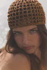 Gorro tipo casquete de tejido trenzado con diseño de red, en color marrón oscuro.