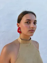 Aros tipo caravanas con diseño de flor irregular en color rojo vibrante y centro con detalle de pequeñas perlas.