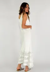 Vestido largo negro con breteles finos y escote redondo. Presenta tres volados de encaje calado en el ruedo.