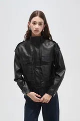 Campera de eco-cuero negro con cuello alto, cierre frontal, bolsillos con solapa en el pecho y puños y ruedo elásticos.