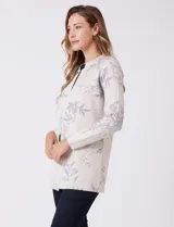 Cárdigan de punto marca Sioni, color beige con estampado floral en tonos azules. Presenta escote redondo a la base, cierre frontal con un botón metálico y mangas largas de corte recto.