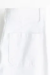 Jean de tiro alto con corte acampanado desde la rodilla. Presenta bolsillos tipo parche en la parte frontal y cierre con botón metálico.