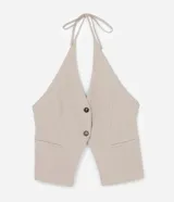 Chaleco color beige con escote halter, corte al cuerpo y cierre frontal con botones. Presenta un bolsillo de ojal en el frente.