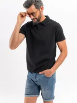 Chomba negra de tejido cloqué, de manga corta con cuello polo y cierre frontal con botones.