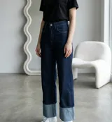 Pantalon jean de tiro alto y corte recto, confeccionado en denim azul oscuro con un llamativo ruedo doblado en tono azul claro que genera un efecto de contraste.