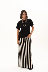 Pollera larga de tejido de punto con diseño de rayas verticales en color negro y crudo. Presenta una pretina elástica con cordón de ajuste y tajos laterales profundos que aportan movimiento.
