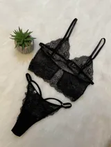 Conjunto de lencería compuesto por un bralette de encaje con breteles ajustables y una tanga de encaje con tiras laterales decorativas.