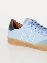 Zapatillas urbanas acordonadas celestes, con recortes en cuero y logo JCH bordado en los laterales.