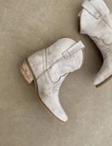 Bota corta estilo western de cuero color marrón, con taco cuadrado de 5 cm y diseño clásico. Presenta un acabado desgastado en la puntera y el talón.