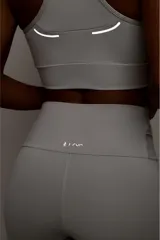 Top deportivo de alto rendimiento con diseño de espalda nadador, confeccionado en tejido técnico con protección UV50+. Presenta un bolsillo interno en el forro frontal y detalles reflectivos.