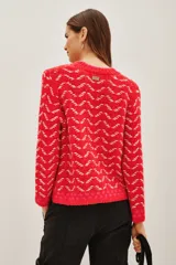Sweater de punto con diseño de patrón geométrico en colores rojo y blanco, cuello redondo y mangas largas.