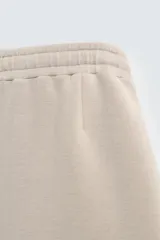 Bermuda de corte oversize confeccionada en tejido técnico compacto con elasticidad. Presenta cintura elástica ajustable con cordón, pinzas en el delantero y la espalda, y bolsillos laterales.