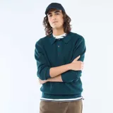 Sweater de punto gofrado en color azul petróleo, con cuello tipo polo y cierre frontal de tres botones. Presenta mangas largas con puños acanalados y un diseño de calce estándar.