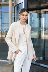 Blazer sastrero color beige, de corte clásico, con solapa de muesca, cierre frontal con un botón, bolsillos delanteros con solapa, manga larga y abertura en la espalda.