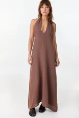 Vestido largo marrón de corte fluido y caída recta, con escote halter y tirantes anchos.