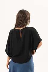 Blusa de silueta relajada y caída fluida, color negro, con escote redondo y mangas amplias.
