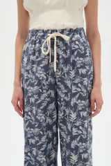 Pantalón de algodón estampado con diseño botánico de hojas en tonos verdes sobre base blanca, de corte holgado, tiro medio y cintura elástica con cordón de ajuste ajustable.