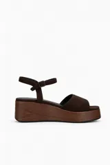 Sandalias de plataforma con efecto madera y terminación gamuzada, con tira en la parte delantera y pulsera ajustable al tobillo con hebilla.