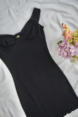 Vestido corto negro con breteles finos, escote en V y detalle de broderie en los bordes.