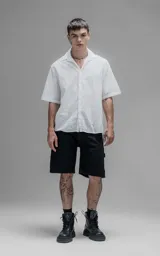Camisa oversize blanca de manga corta y cuello abierto, confeccionada en algodón con diseño bordado.