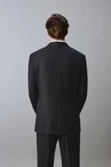 Blazer de corte regular fit confeccionado en lana italiana, con diseño de raya diplomática. Presenta cuello con solapas de pico, cierre frontal de botonadura cruzada, bolsillos de vivo en el pecho y bolsillos de solapa en la cadera.