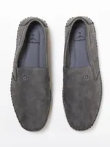 Mocasín negro de cuero sintético, con elástico en los laterales y suela de goma.