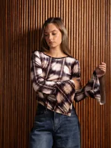 Blusa de terciopelo con estampado a cuadros, corte asimétrico y mangas largas acampanadas.