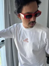 Remera blanca de manga corta con cuello redondo y corte holgado. Presenta un estampado gráfico en la espalda con elementos marinos (sol, ola, estrella de mar, flor, etc.) y el texto "VITAMIN SEA" y "BROKERS".