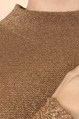 Suéter de punto con acabado metalizado en color dorado, de silueta holgada, cuello alto y mangas largas con puños ajustados.