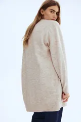 Saco largo de punto fino color beige, con lana en la trama, hombros caídos y ribete acanalado en nuca, puños y bajo. No tiene cierre.