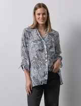 Camisa estampada con hojas en tonos celeste, naranja y verde. Tiene cuello con solapa, abertura central con botones, bolsillos aplicados en la parte delantera y mangas 3/4 con lazo.