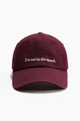 Gorra de sarga de algodón color bordó con bordado frontal con la frase "I'm not in the mood." en color blanco.